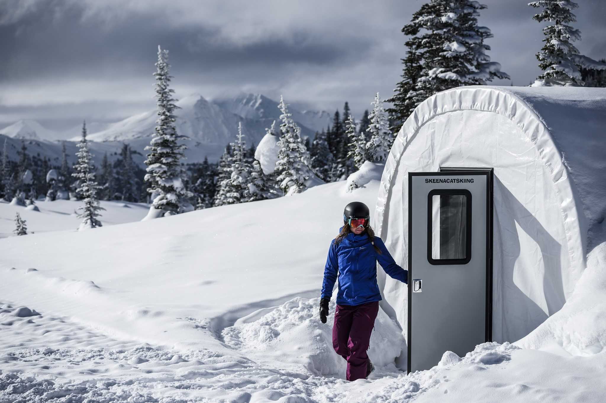 Women dressed in ski gear exiting tent in snowy landscape