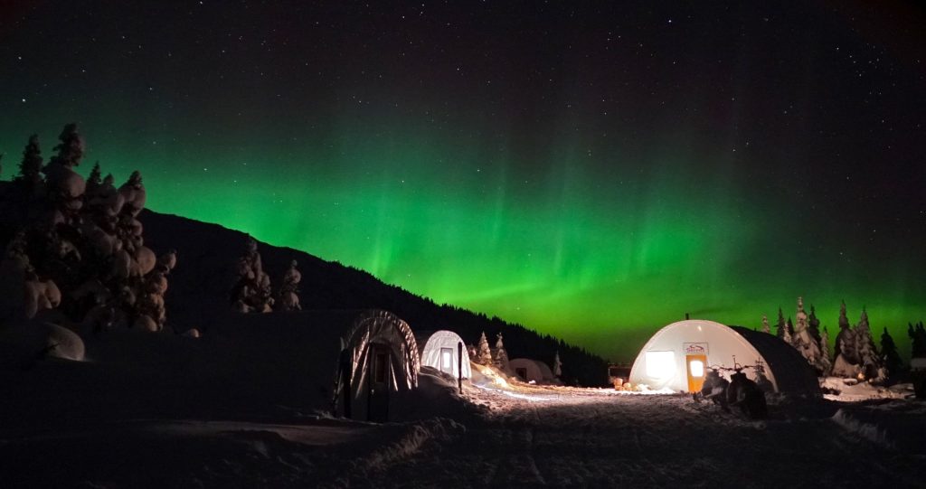 Tents under the Aurora Borealis in the snowy landscape of British Columbia